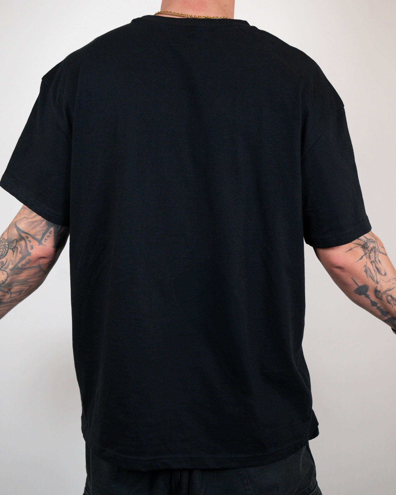 Rückansicht eines schlichten schwarzen T-Shirts ohne Aufdruck oder sichtbare Details. Die Ärmel reichen bis knapp über die Ellenbogen. Das Shirt wird locker getragen.

